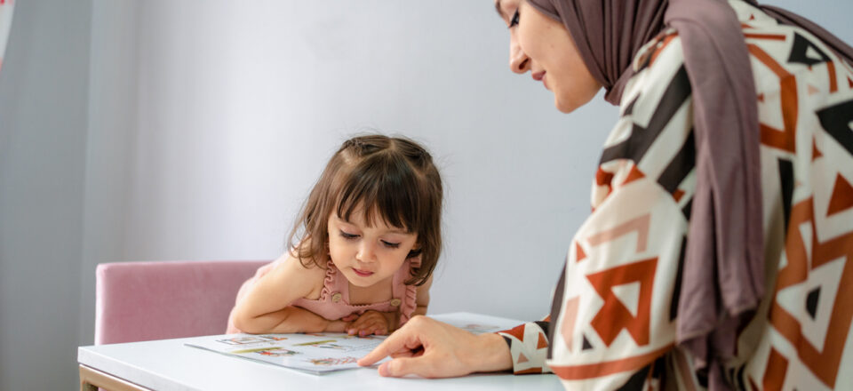 Training and education of children, a girl with her mother and a book at home read a textbook