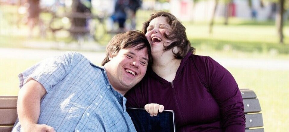 Couple in love of 26 years old Down Syndrome in a park in Montreal doing selfie with mobile phone. They are learning to live independently.  Color and horizontal photo was taken in Quebec Canada.