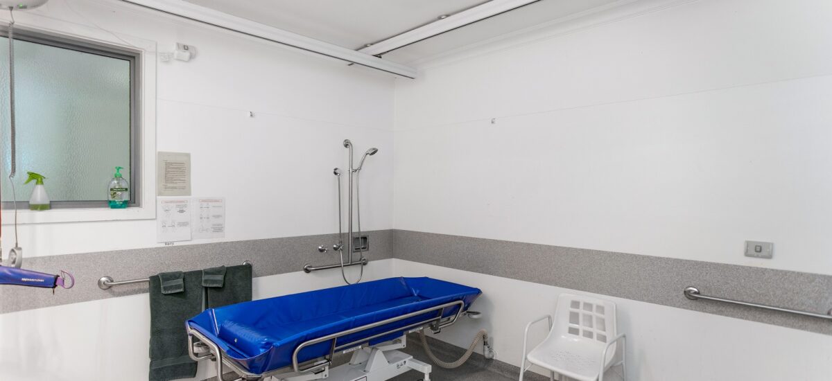 Accessible bathroom with a shower bed, grab rails and ceiling hoist