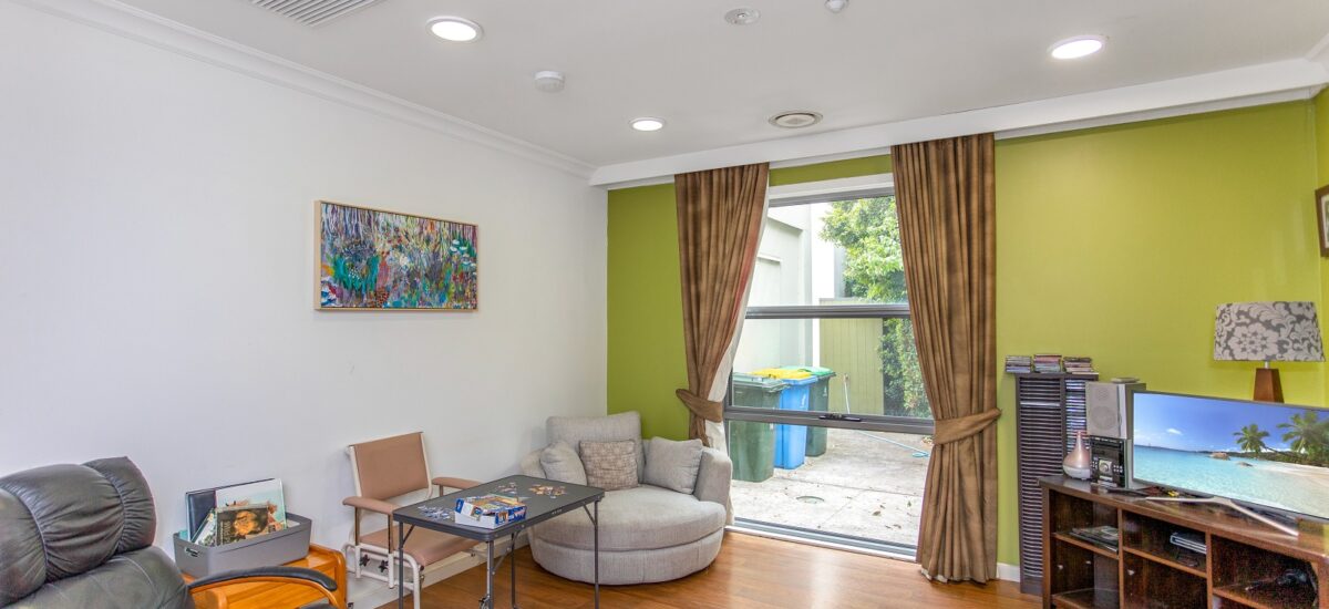Living room with chairs, a green feature wall and a TV