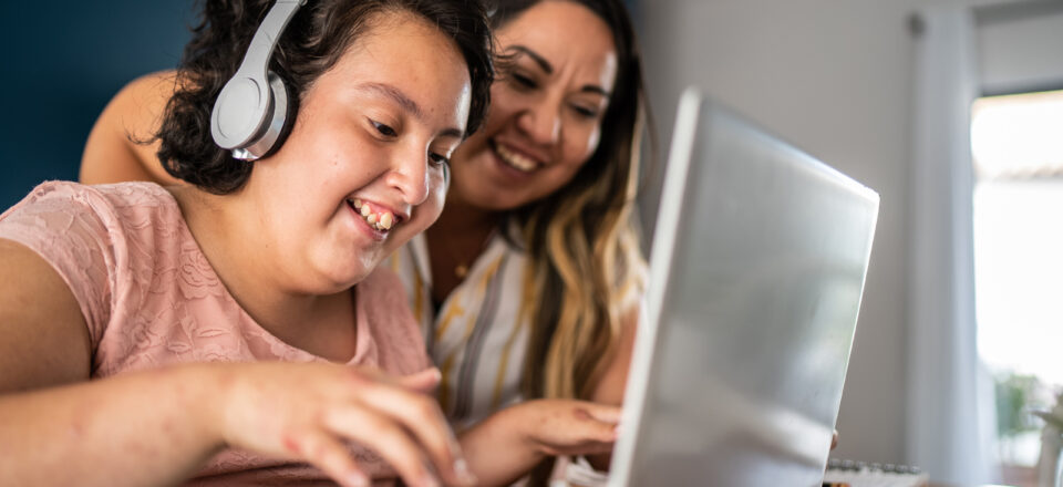 Mother helping psychomotor retardation girl using laptop studying at home